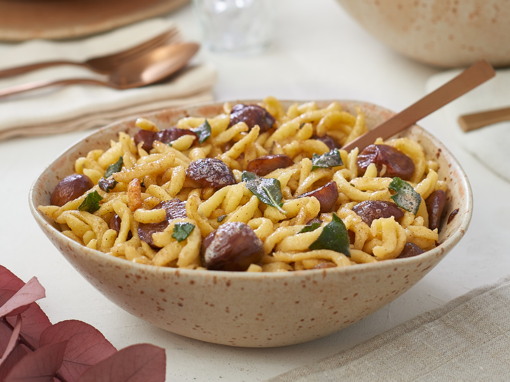 Spätzle mit Maronengemüse und Salbei Eine Schüssel Pasta mit Fleischbällchen auf einem Tisch.