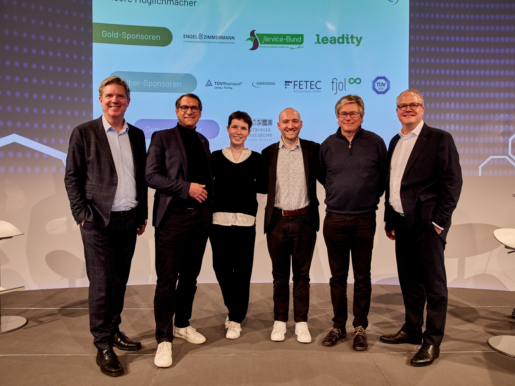 Eine Gruppe von Menschen steht vor einem großen Bildschirm.